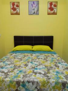 ein Bett in einem Schlafzimmer mit drei Bildern an der Wand in der Unterkunft Mutiara Inn GuestRoom in Kampung Gurun