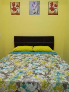 Mutiara Inn GuestRoom في Kampung Gurun: سرير في غرفة نوم مع ثلاث صور على الحائط