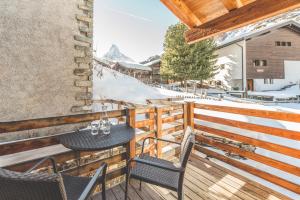 einen Balkon mit 2 Stühlen und einem Tisch an einer Skipiste in der Unterkunft Chalet Alpoase in Zermatt