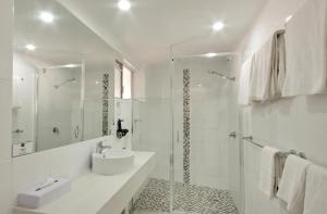 y baño blanco con lavabo y ducha. en Colonial Palms Motor Inn, en Airlie Beach