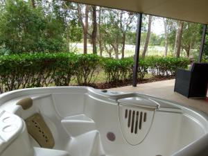 a white bath tub sitting on a patio with trees at Lake Russell Lakeside Retreat in Emerald Beach