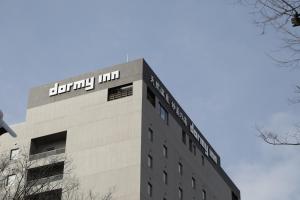 a building with a sign on the top of it at Dormy Inn Maebashi in Maebashi