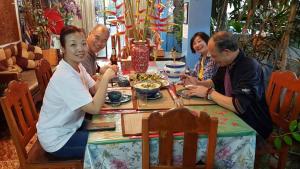 Un groupe de personnes assises autour d'une table et mangeant de la nourriture dans l'établissement Saithong House, à Chiang Mai