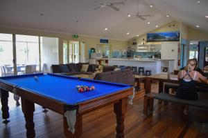 a woman sitting in a living room with a pool table at Hervey Bay Flashpackers in Hervey Bay