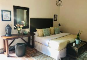 1 dormitorio con cama, mesa y espejo en Hotel Real de Piedra, en Pénjamo