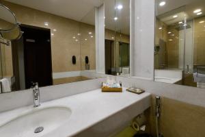 a bathroom with a sink and a large mirror at Faisalabad Serena Hotel in Faisalabad
