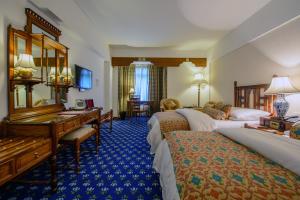 a hotel room with three beds and a desk at Faisalabad Serena Hotel in Faisalabad