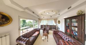 a living room with leather couches and a balcony at Sunčani Breg Apartments Vrdnik in Vrdnik