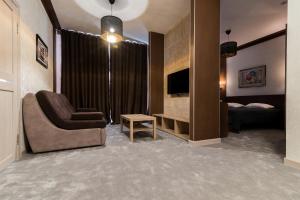 uma sala de estar com um sofá e uma cadeira e uma televisão em LaCasa Hotel em Karaganda