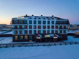 un gran edificio con un cartel en la nieve en LaCasa Hotel en Karagandá