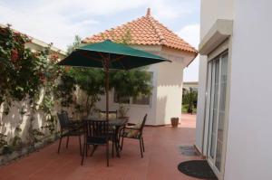 einen Tisch und Stühle mit einem grünen Sonnenschirm auf einer Terrasse in der Unterkunft villa térangart saly in Saly Portudal