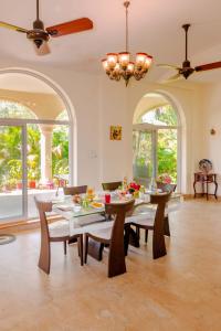 a dining room with a table and chairs and windows at SaffronStays La Casa Maestro, Kashid - spanish-style luxury villa near Kashid Beach in Kashid