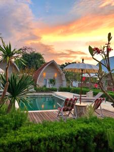 a swimming pool with two chairs and an umbrella at La Roja Bungalows in Nusa Penida