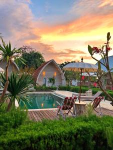- une piscine avec 2 chaises et un parasol dans l'établissement La Roja Bungalows, à Nusa Penida