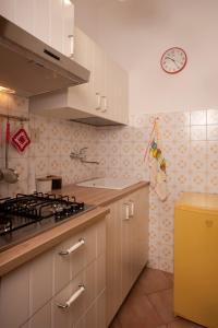 eine Küche mit weißen Schränken und einer Uhr an der Wand in der Unterkunft La Casetta di Maria in Lido di Venezia