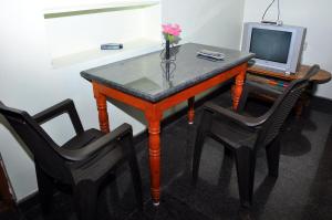 a table with a vase of flowers and a tv at Srinivasa Homestay in Hampi