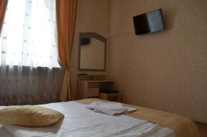 ヴィーンヌィツャにあるGostiniy Dvorのベッドルーム1室(ベッド1台、壁掛けテレビ付)