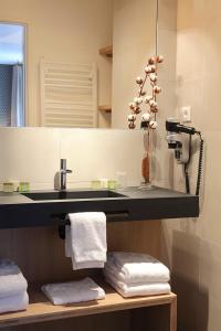 a bathroom with a sink and a mirror and towels at Logis Hotel de la Nivelle in Saint-Pée-sur-Nivelle