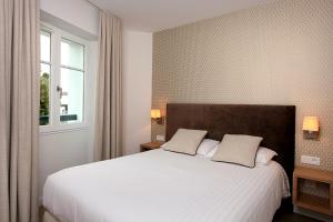 een slaapkamer met een groot wit bed met 2 kussens bij Logis Hotel de la Nivelle in Saint-Pée-sur-Nivelle