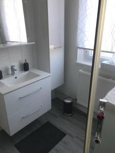 une salle de bain blanche avec un lavabo et un miroir dans l'établissement Appartement proche Mer, à Berck-sur-Mer