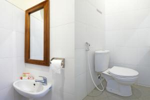 a white bathroom with a toilet and a sink at Grha Vege Jawi Syariah Mitra RedDoorz in Yogyakarta