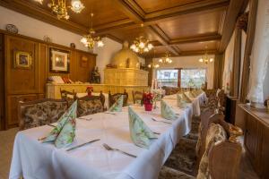 a dining room with white tables and chairs and chandeliers at Hotel Hirsch in Bad Peterstal