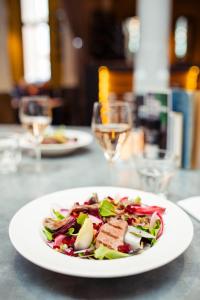 um prato branco com uma salada na mesa em Post-Plaza Hotel & Grand Café em Leeuwarden