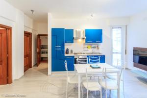 een keuken met blauwe kasten en een witte tafel en stoelen bij appartamento ristrutturato a nuovo !!! in Varazze