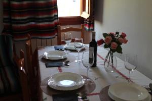 a table with plates and glasses and a bottle of wine at Apartamentos Rurales Rosendo: El Celindo in Capileira