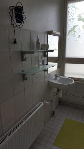 La salle de bains blanche est pourvue d'un lavabo et d'une fenêtre. dans l'établissement Ribere Apartment, à Pärnu