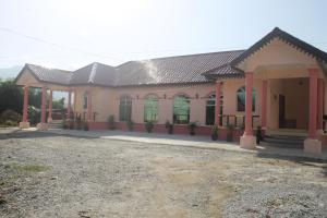 a pink building with green doors on it at Malinja Home in Pantai Cenang