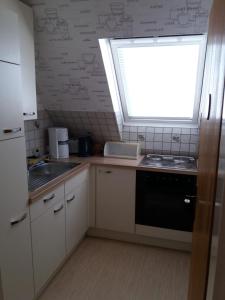 a kitchen with a window and a sink and a stove at Pension-Stürrad in Neuharlingersiel