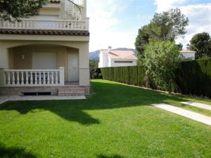 a house with a porch and a yard with green grass at MEDDAYS CHALET EUCALIPTUS 6 in Miami Platja