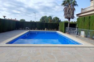 a swimming pool in a yard with a fence and a palm tree at MEDDAYS CHALET EUCALIPTUS 6 in Miami Platja