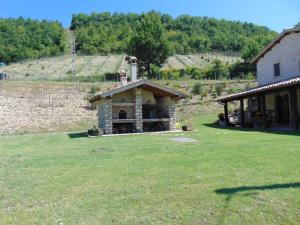 a building with a fireplace in a field of grass at Agriturismo Rocca del Nera in Preci