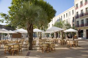 een patio met tafels, stoelen en parasols bij Hôtel le XIX in Béziers