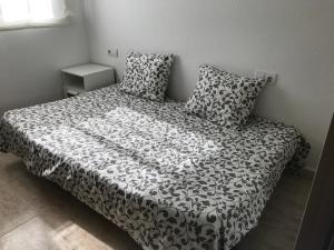 a bed with a black and white comforter and two pillows at MEDDAYS CHALET EUCALIPTUS 6 in Miami Platja +18 photos
