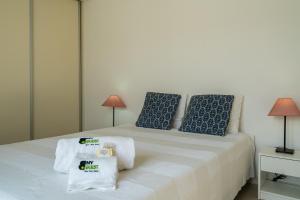 uma cama branca com almofadas azuis e toalhas em BmyGuest - Santa Luzia Sunset Apartment em Tavira