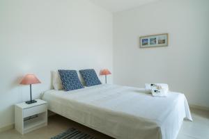 um quarto branco com uma cama grande e almofadas azuis em BmyGuest - Santa Luzia Sunset Apartment em Tavira