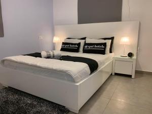 a white bed with black and white pillows on it at Spat Apartments in Bat Yam