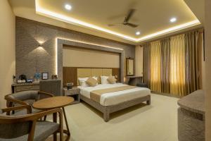 a hotel room with a bed and a table and chairs at Hotel ARJUNAA in Rāmeswaram