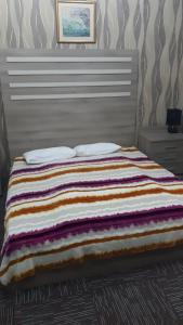 Una cama con una manta de colores encima. en AZPETROL HOTEL GAZAX, en Qazax