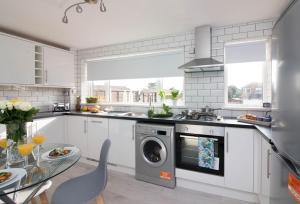 cocina con armarios blancos y lavavajillas en Foxcroft en Brighouse