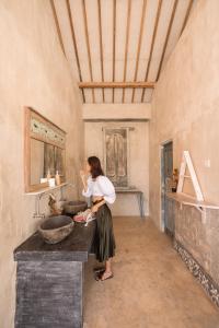 een vrouw in een badkamer met een wastafel bij La Roja Bungalows in Nusa Penida