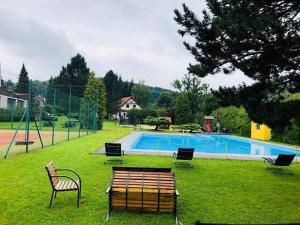a park with a bench and chairs next to a pool at Hotel Slatina in Lipova Lazne