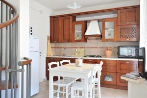 a kitchen with a white table and white chairs at Casa Bianco Navarrese A in Santa Maria Navarrese