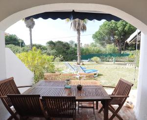 a wooden table with chairs and an umbrella on a patio at E&M Beach House Aldeamento do Levante III in Porches