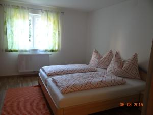 una camera da letto con letto, cuscini e finestra di Ferienwohnungen Resch a Eckberg