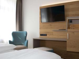 a hotel room with a tv and a bed and a chair at Hotel Ross in Meißen