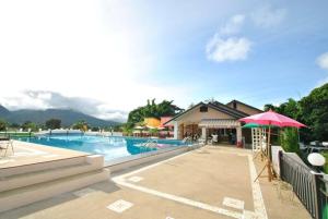 a swimming pool with an umbrella and a resort at Baan Kung Kang De Pai in Pai